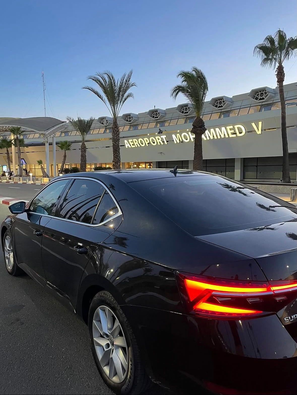 Aeroport Mohammed V terminal facade with palm trees at dusk, Casablanca