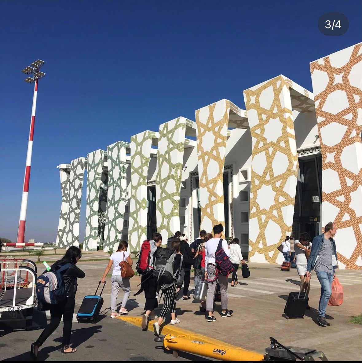 Travellers walking past the geometric-patterned facade of Fès–Saïss Airport