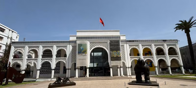 Arcaded white facade and Moroccan flag at the Mausoleum of Mohammed V complex, Rabat