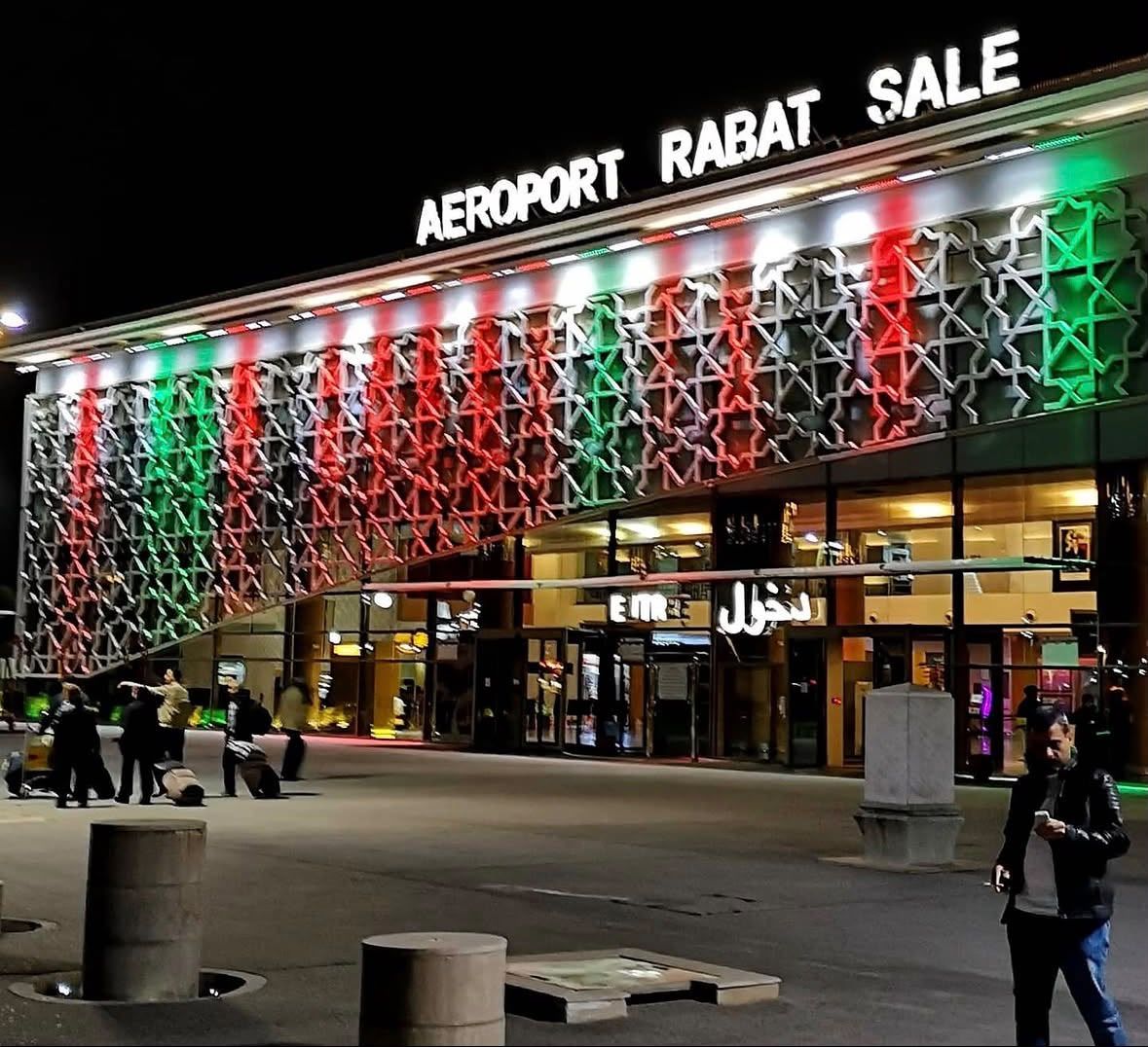 Rabat–Salé Airport facade lit red, green and white at dusk